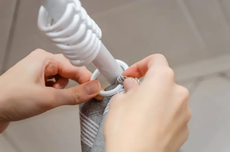 Person removing shower curtain rings for cleaning