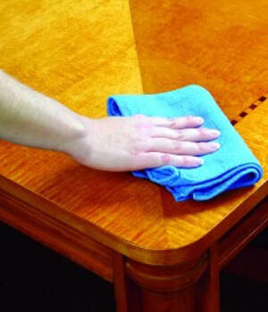 person cleaning a coffee table with a microfiber cloth