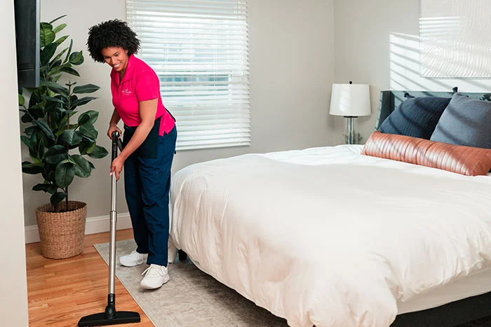A Molly Maid home professional cleaning a bedroom 