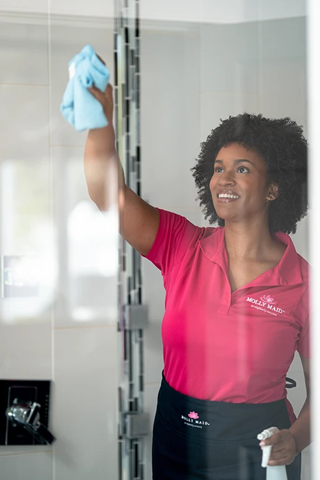 A Molly Maid professional wiping shower door at a move-out cleaning appointment 